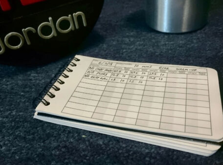 The Pocket Gym Diary with a workout recorded, next to a dumbbell and sports drink bottle.