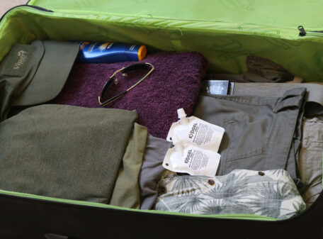 Two pouches of Exogel Camping Stove Gel Fuel packed into a suitcase with other luggage, ready for air travel.