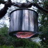 Burning Exogel Camping Stove Gel Fuel applied to the underside of a hanging billy can in the woods, and so heating the pot without need of a stove.