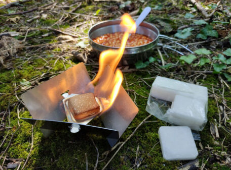 The Stealth Stove burning some solid fuel tablets, being used with the wider base at the top to heat a wide camping pot of baked beans.