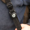 The compass unit attached to a rucksack strap.