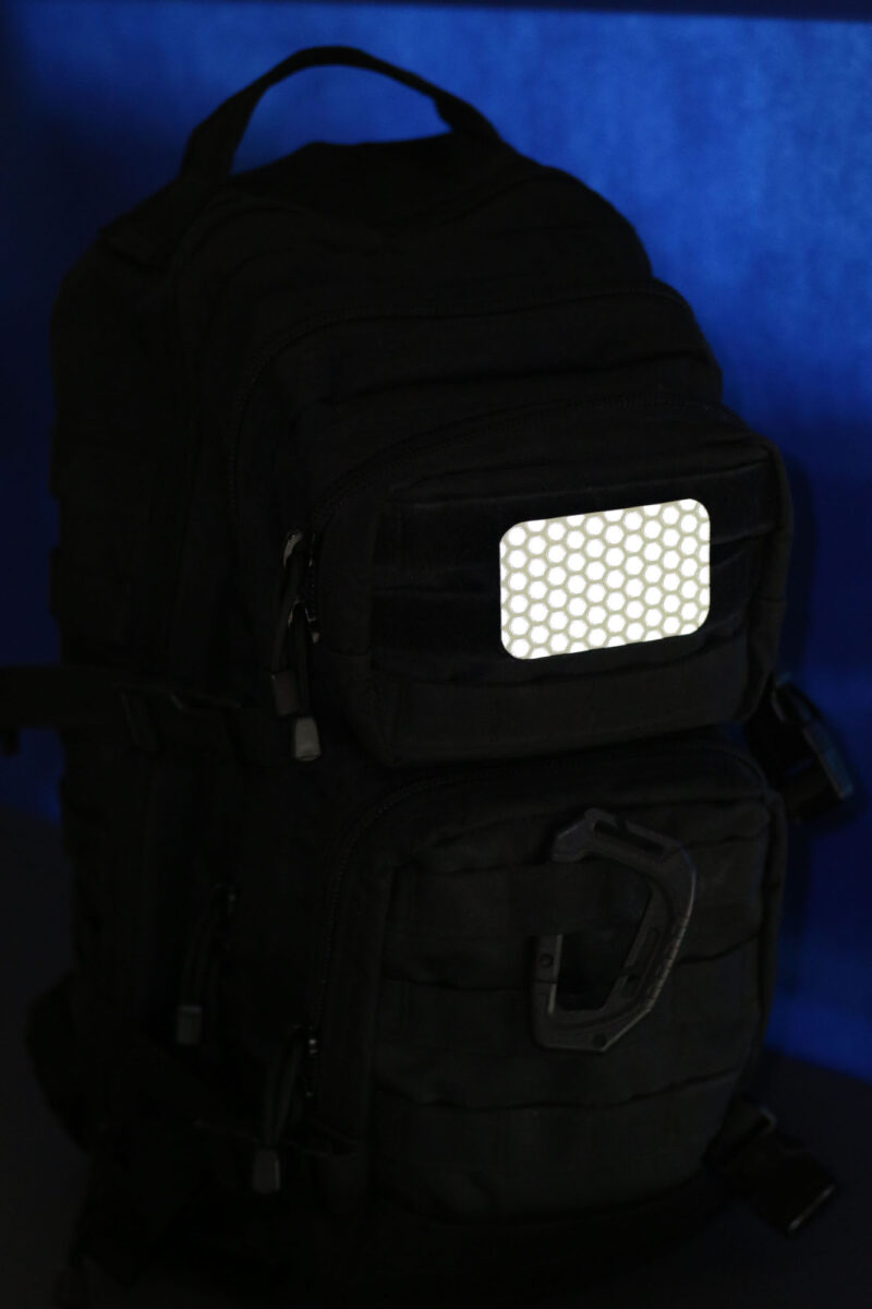 The glinting Cyflect Patch, attached to a tactical black rucksack.
