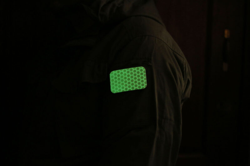 The glowing Cyflect Patch, attached to shoulder of a military jacket.