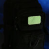The glowing Cyflect Patch, attached to a tactical black rucksack.