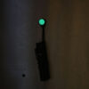 A Magnetag, being used to hang a flashlight from a steel surface, while the glow-in-the-dark element glows bright green as a gear marker.