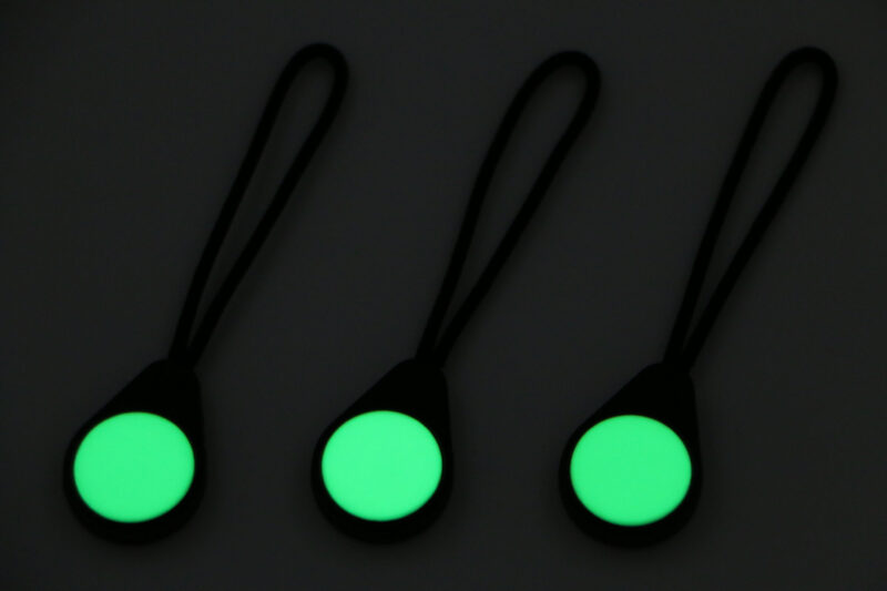 Three Magnetags brightly glowing green against a dimly-lit surface.