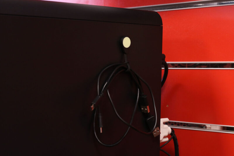 A Magnetag attached to the side of a desktop computer, being used as a USB cable tidy.