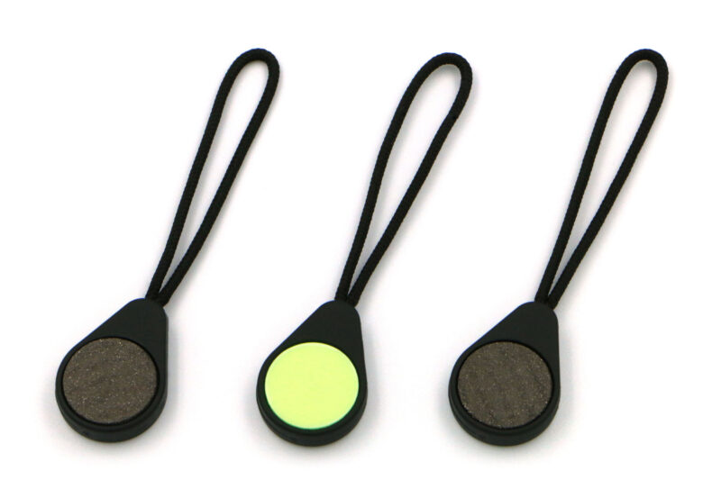 Three Magnetags, showing both the neodymium magnet surface, and the rear glow-in-the-dark marker, on a plain white background.