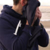 A man wiping his face with the microfibre towel, on a beach.