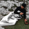 Emergency foil blanket being used in a mountain survival situation.